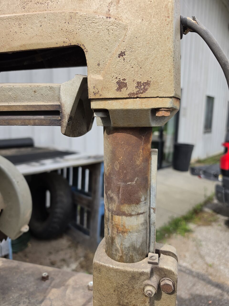 Column and elevation tube beneath the arm, with surface rust on the tube