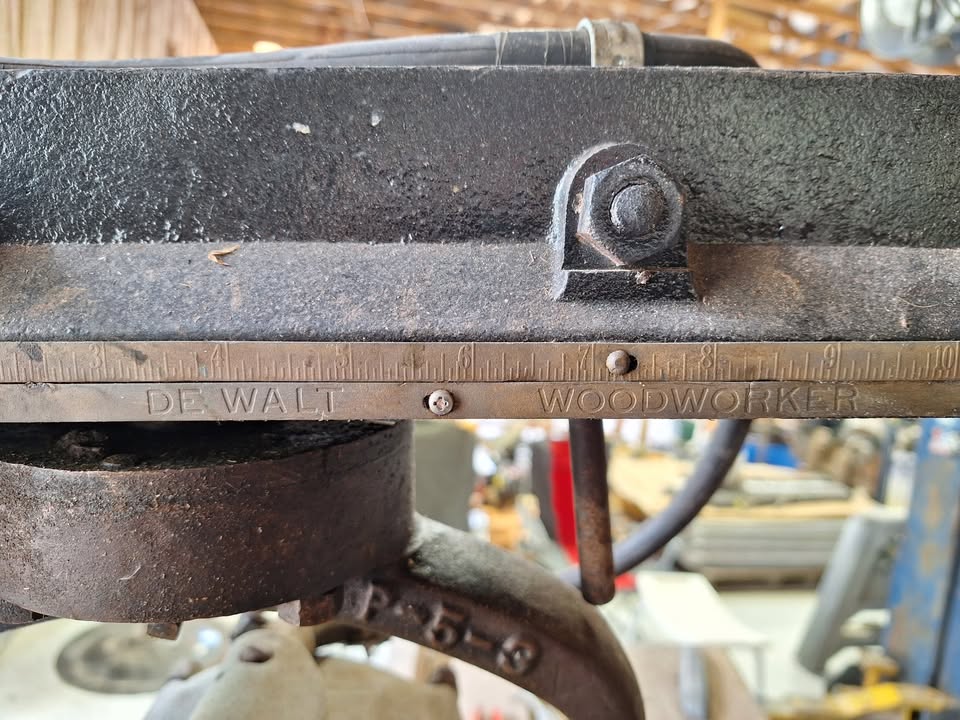 Close-up of the arm rail, stamped DE WALT WOODWORKER, with the rip scale